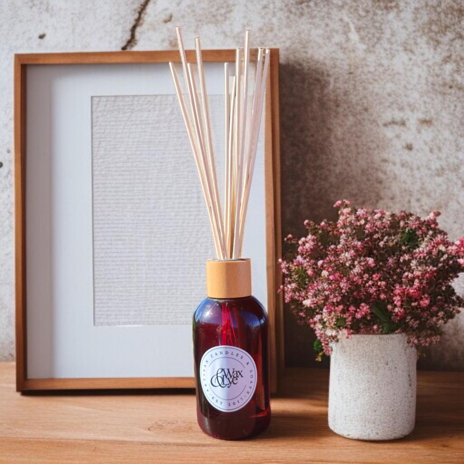 Amber glass reed diffuser with Wax & Lye logo, open and set against a stylised background